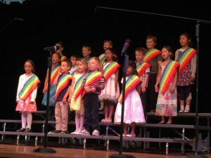 Children standing together on a stage, singing.