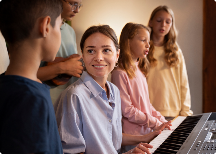 Children standing around a piano singing.